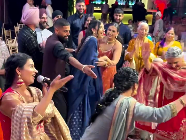 Surleena smiling and singing while family members dance and celebrate together