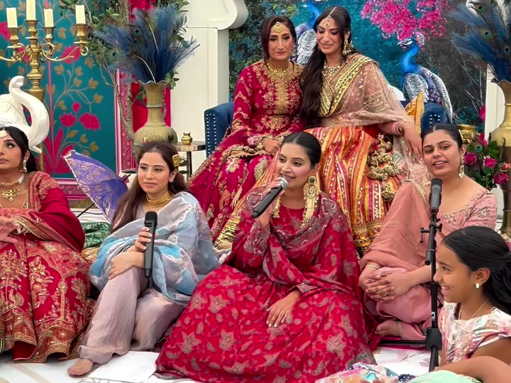 Surleena and fellow singers performing with family seated together at a Mehndi celebration